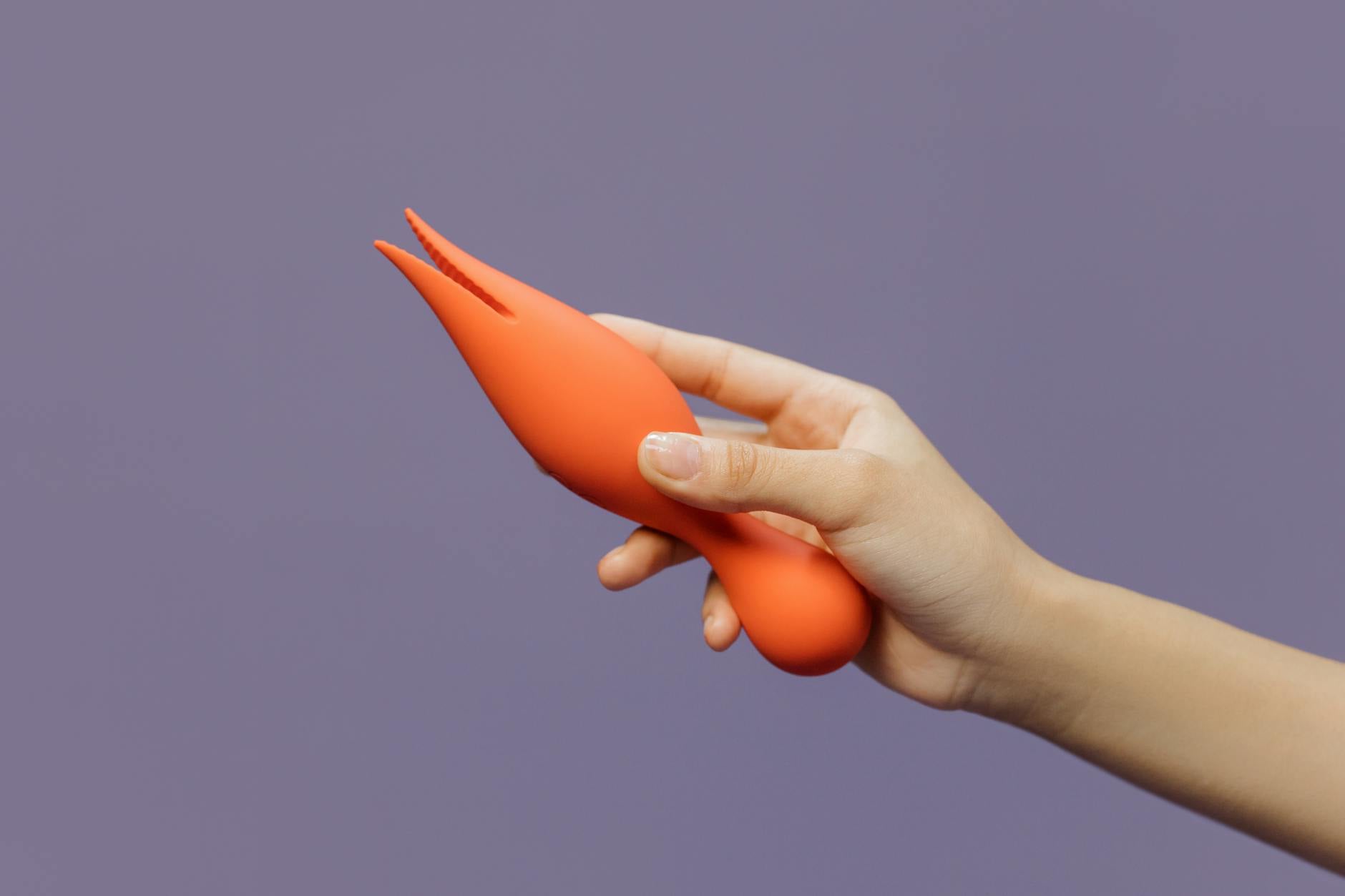 A hand holding a lemon vibrator against a minimalistic purple backdrop, showcasing modern sensuality and pleasure.