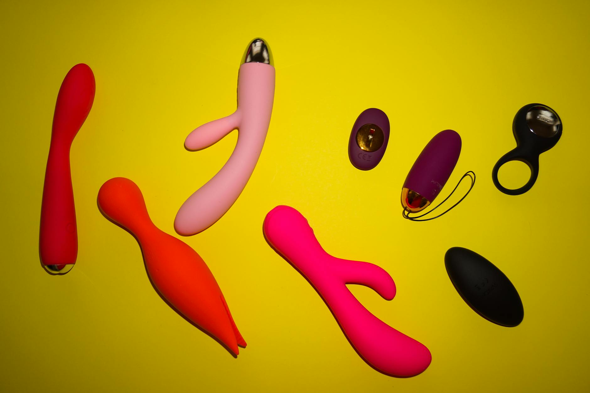 Yellow silicone vibrator surrounded by fresh fruit on a bright background