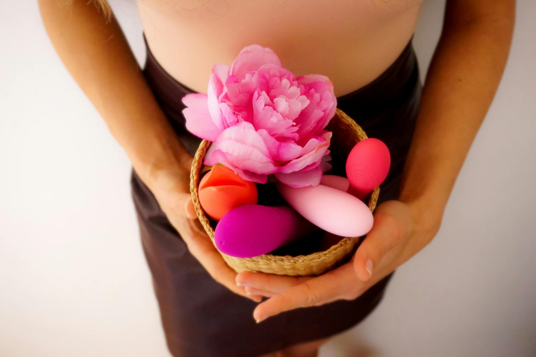 A hand reaching over a variety of colorful clitoral vibrators on a table